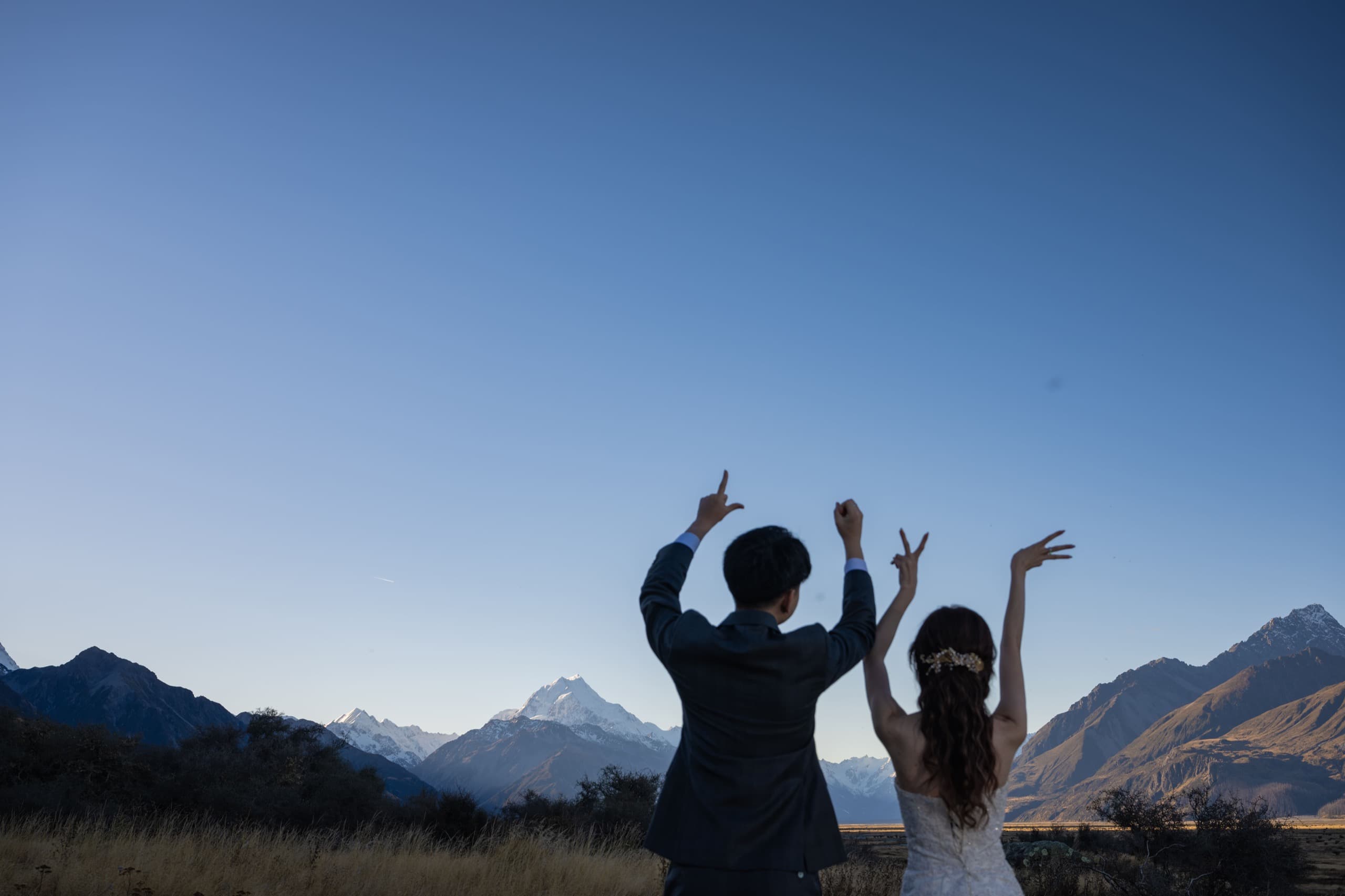 Judy and Lucas raising their arms to a clear alpine sky
