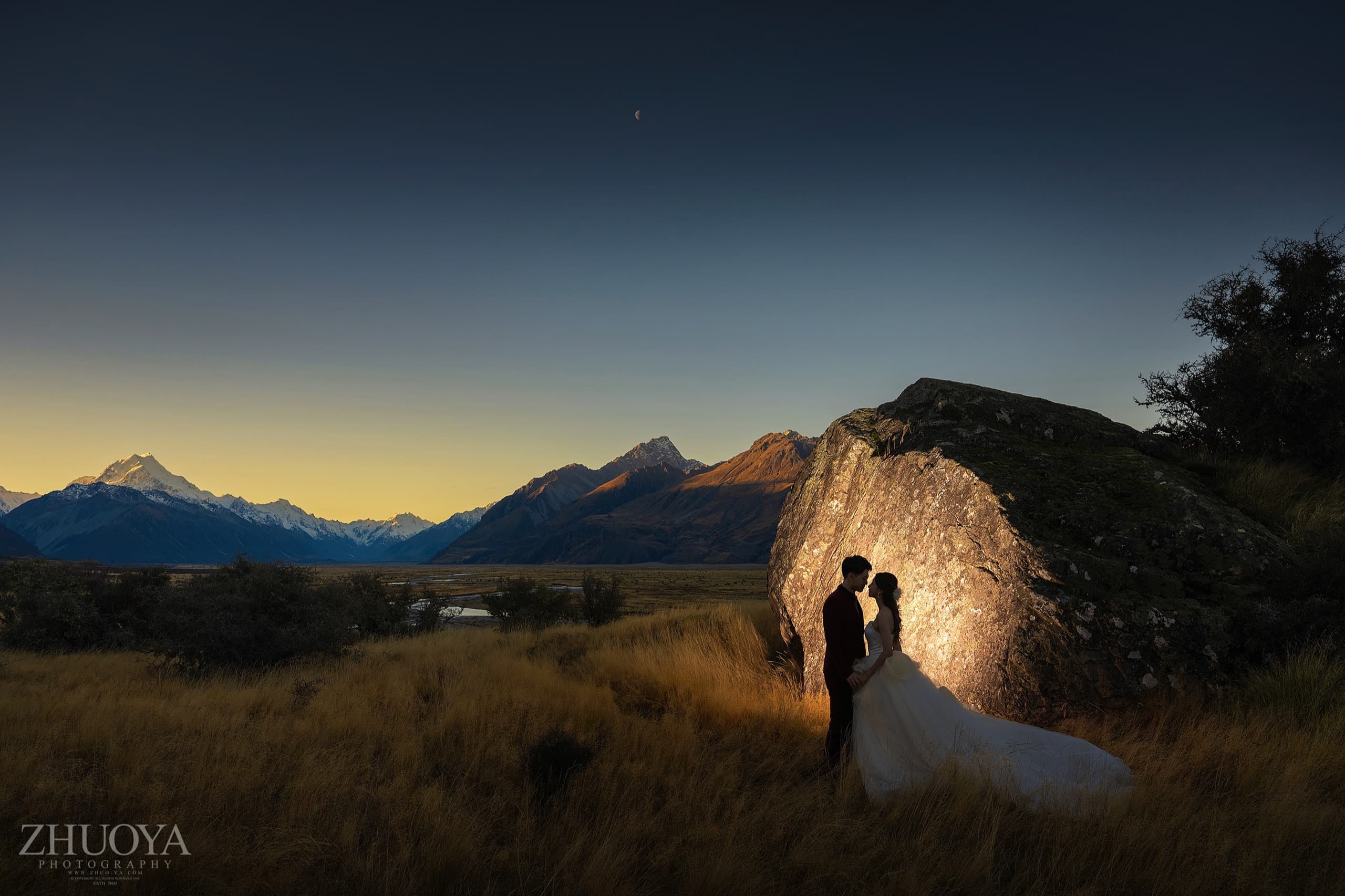 Judy and Lucas at golden hour beside a giant boulder in a mountain valley